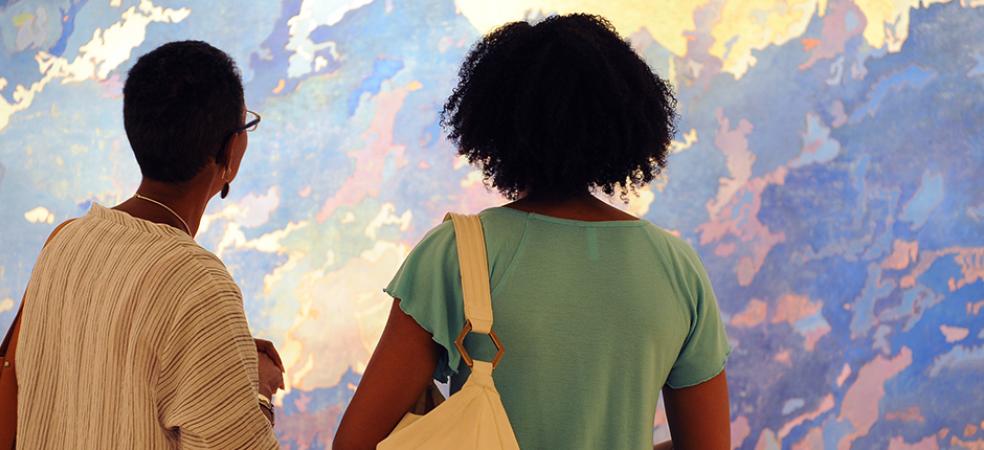 Visitors look at a painting