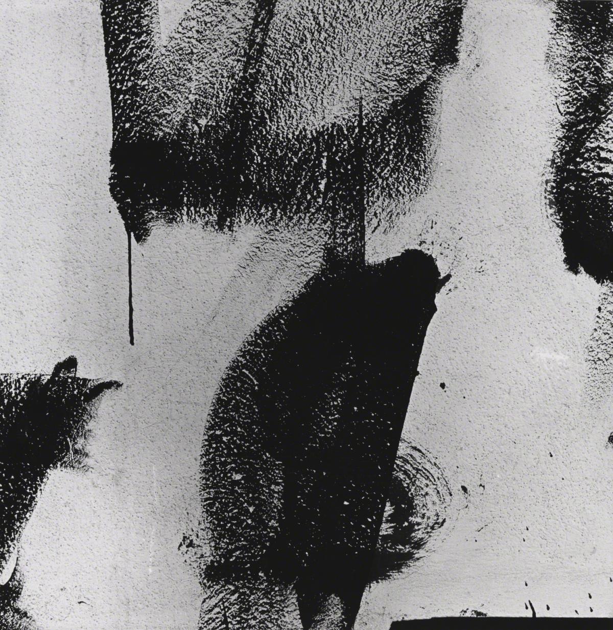 Black and white photograph showing smears of back paint on a white wall