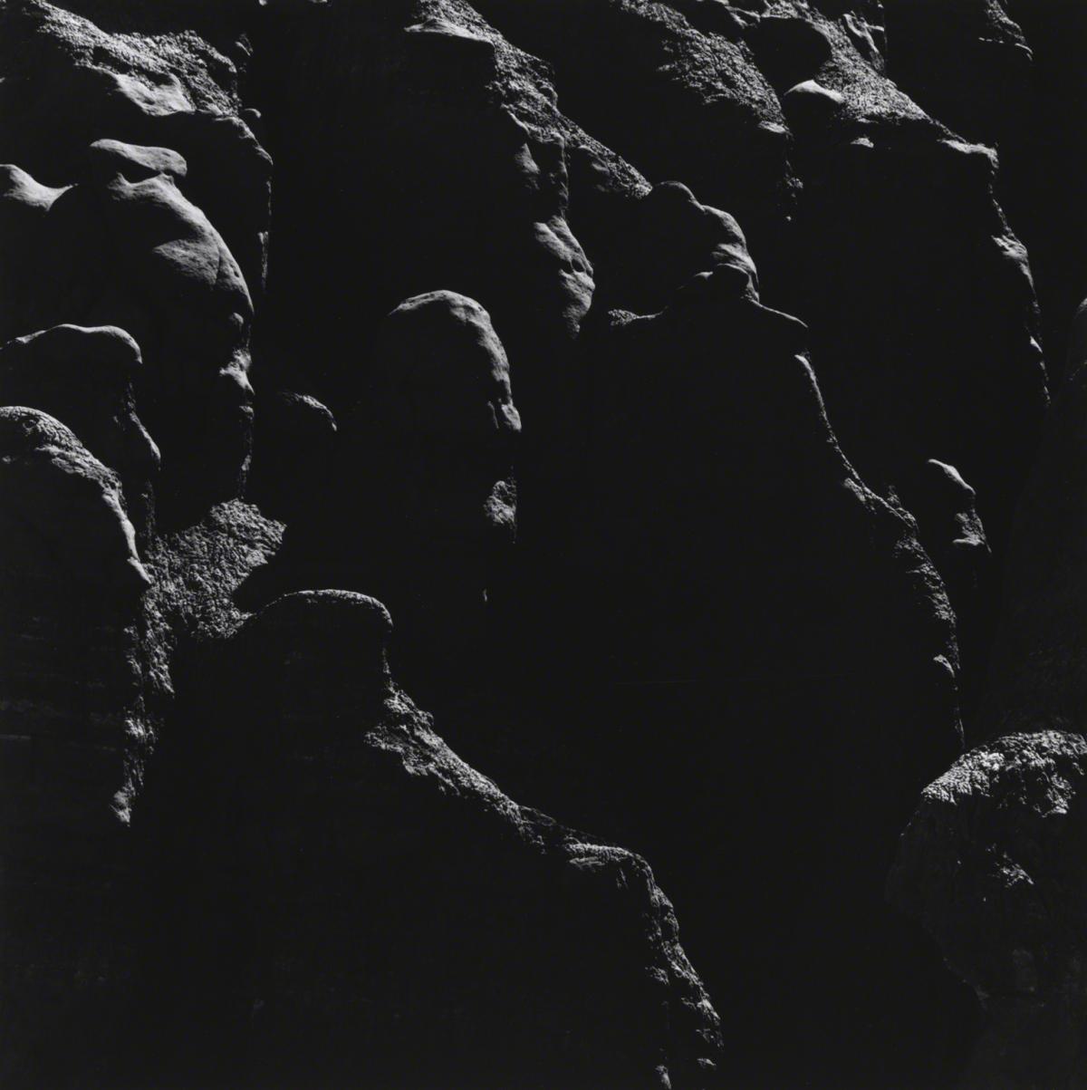 A dark black and white photograph showing a rocky outcropping