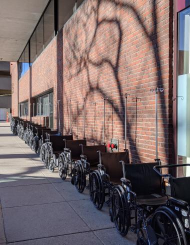 Photograph of a row of wheelchairs against a brick building