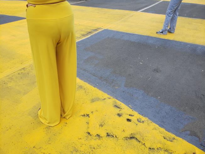 Photograph of someone wearing yellow pants standing on a street painted yellow