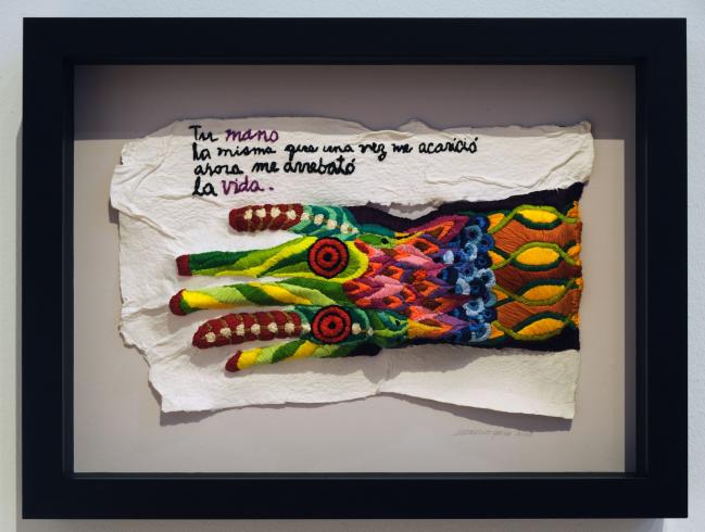 A colorful embroidered hand with a poem above in a black frame