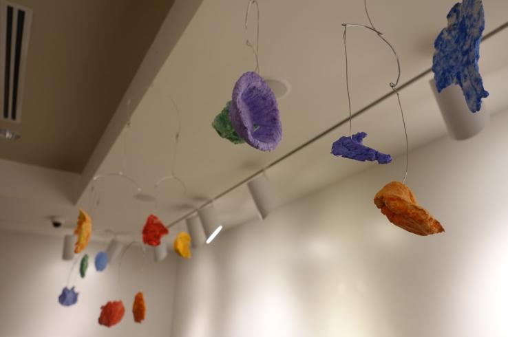 Mobiles with different colored paper mache shapes.