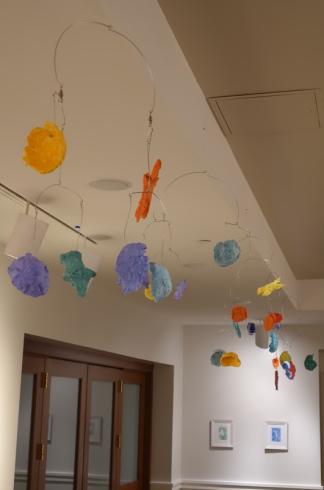 Mobiles with different colored paper mache shapes.