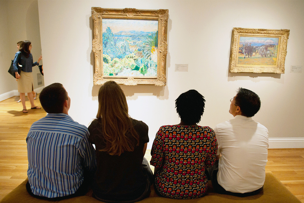 Museum visitors look at paintings