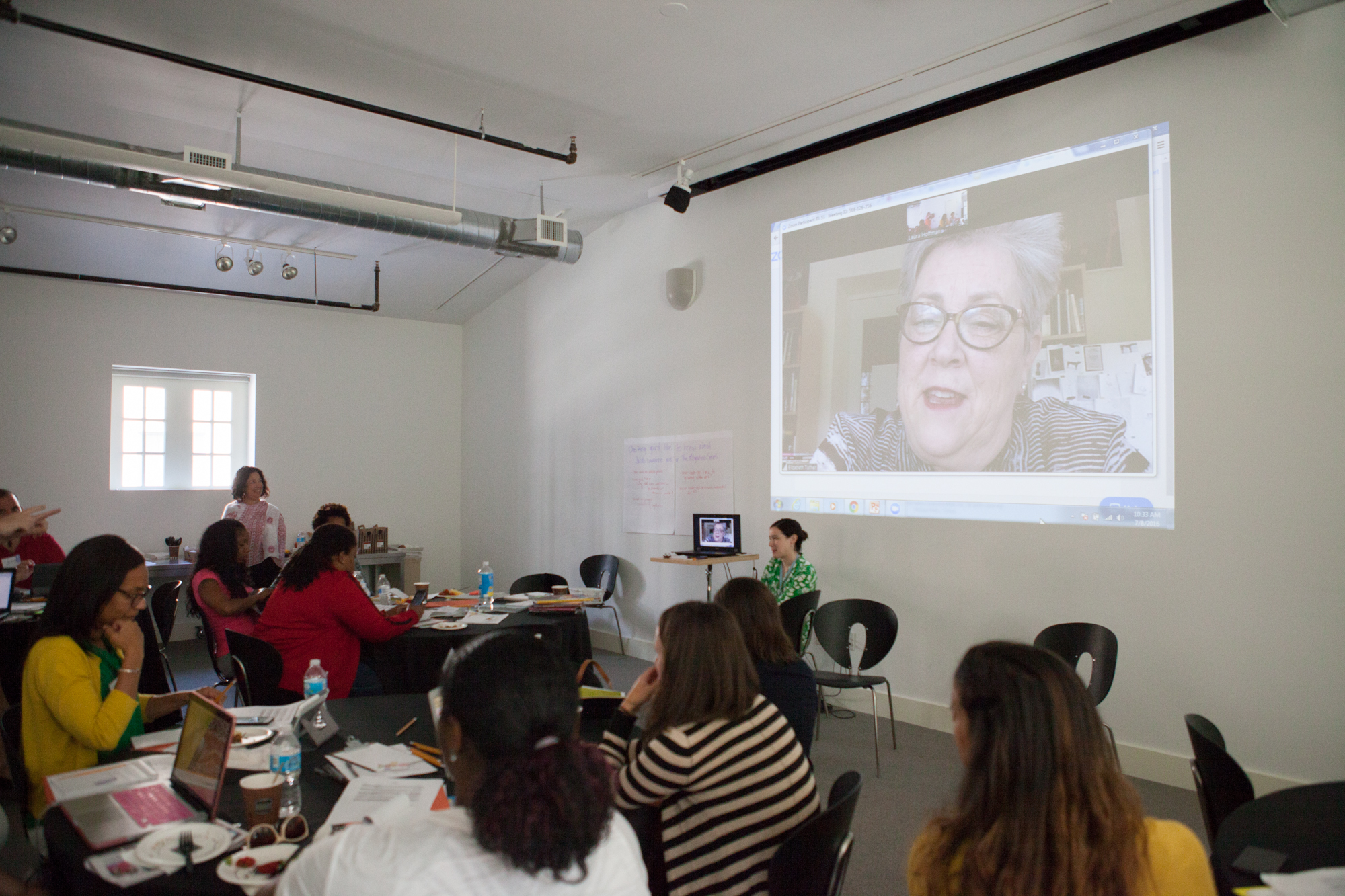 Photograph of the Center Studio with people at tables watching an image projected on the wall