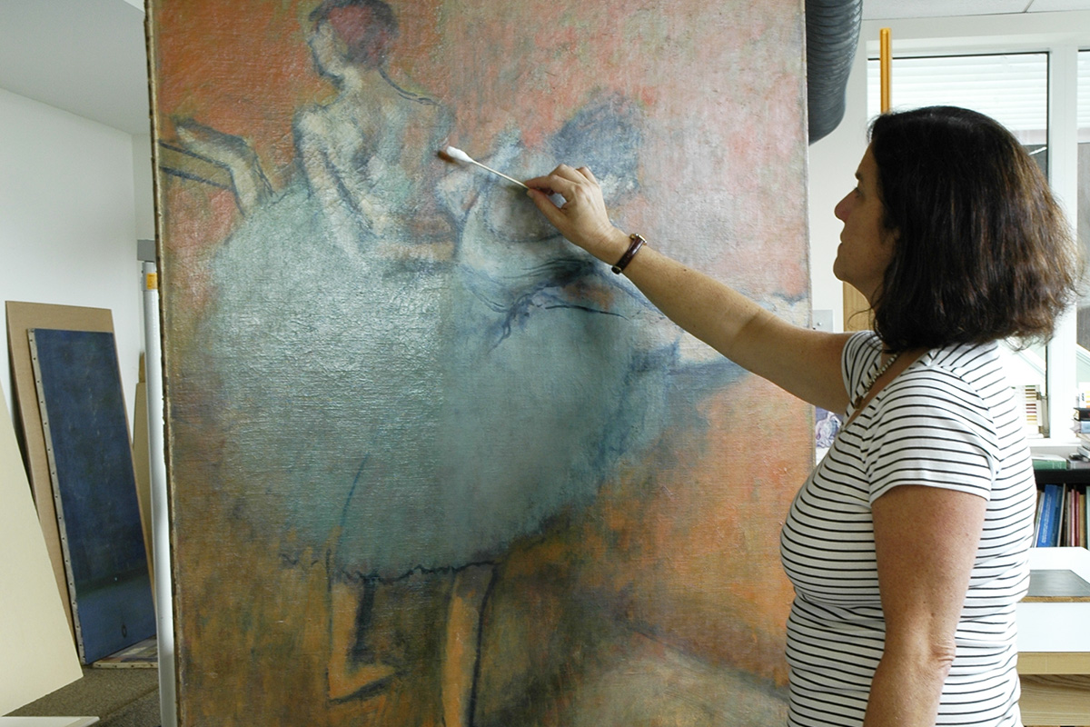 Lilli Steele removing discolored varnish from Degas's Dancers at the Barre.