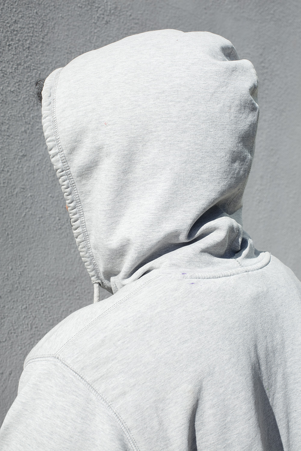 A person in a hoodie stands with their back to the viewer.