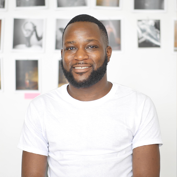 Photo portrait of John Edmonds smiling, with photo collage behind him