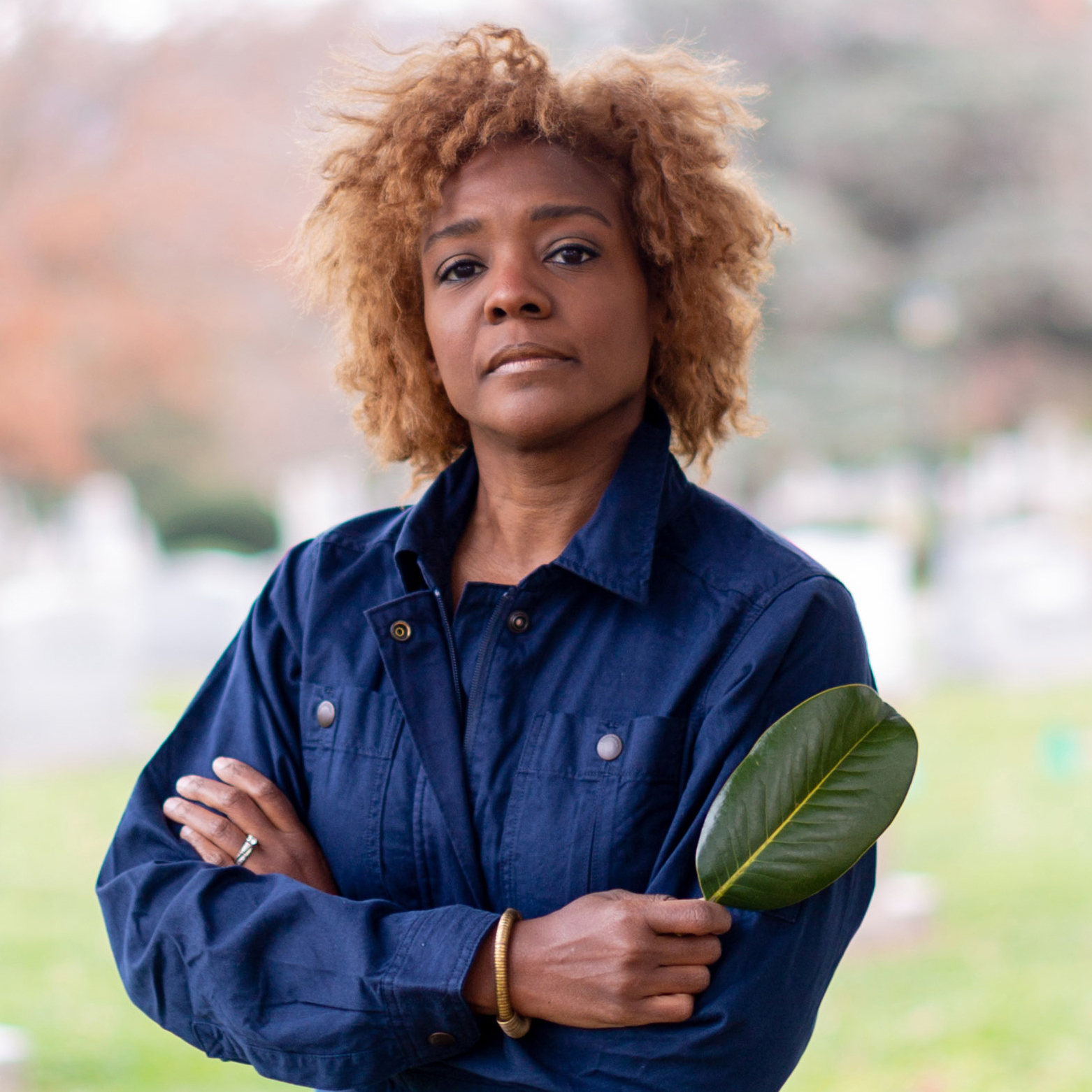 Headshot of Nekisha Durrett, arms crossed and holding a leaf
