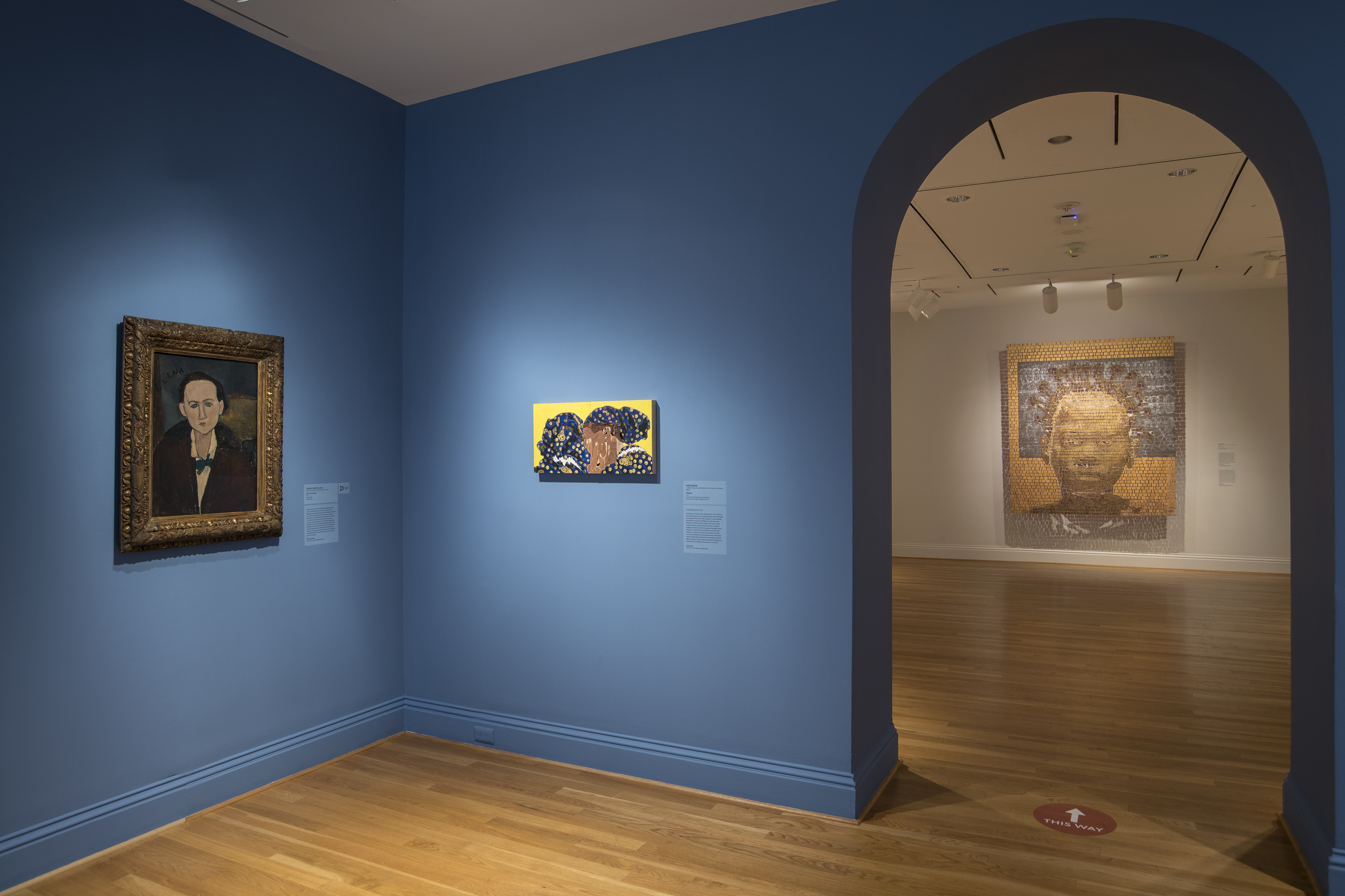 portrait with gilded frame on left, small portrait of two people in middle, and huge mosaic portrait through doorway on right