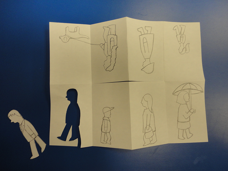 Photograph of a paper with drawn figures and one figure cut out
