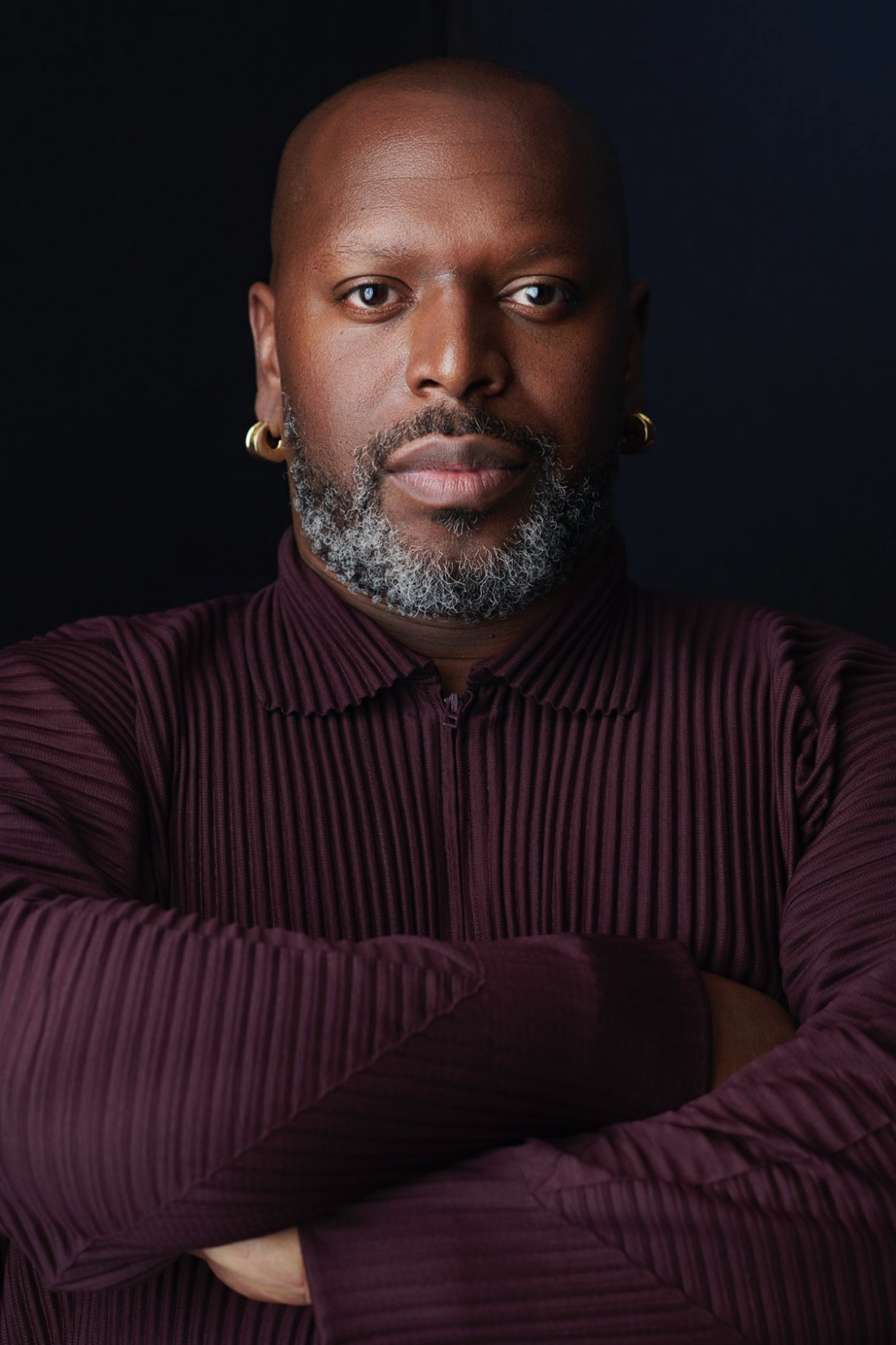 Rashaad Newsome headshot with arms crossed and black background