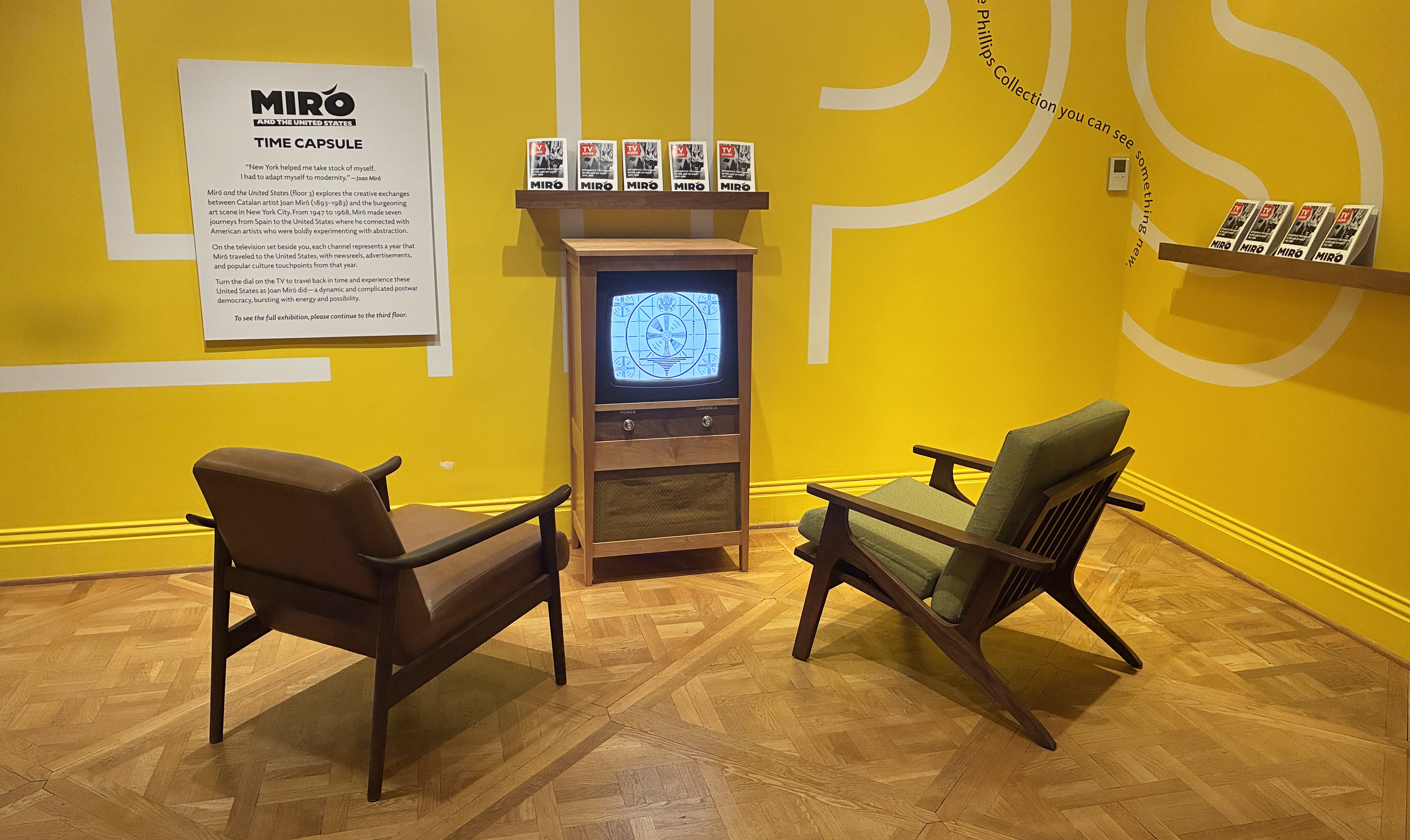 Two chairs in front of a retro tv against a yellow wall 