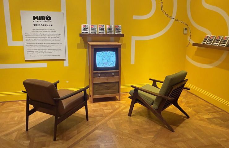 Two chairs in front of a retro tv against a yellow wall 