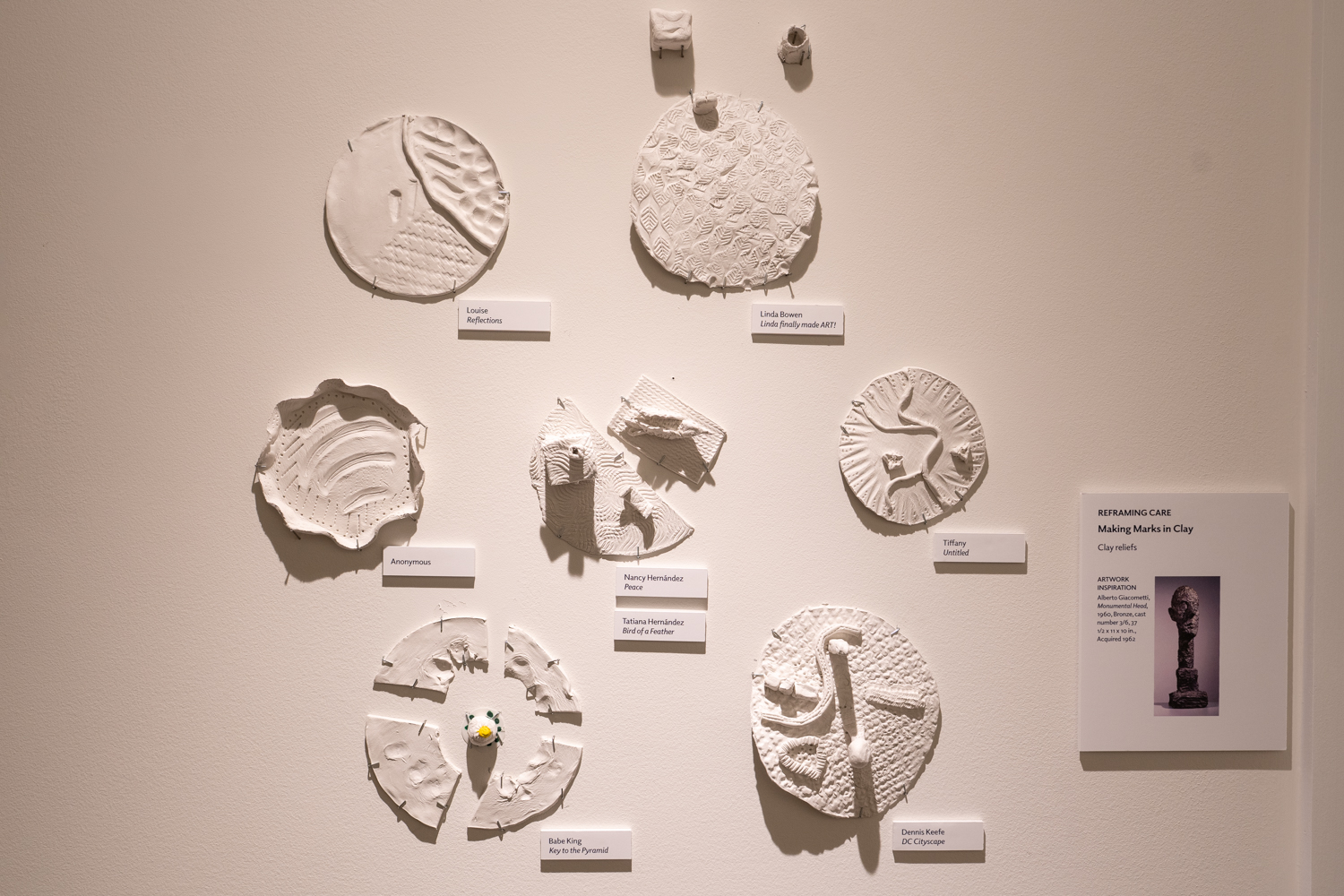 circular white artworks made of clay displayed on a wall