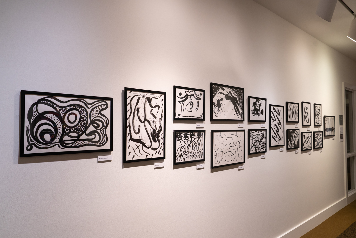 17 black-and-white artworks displayed on a wall