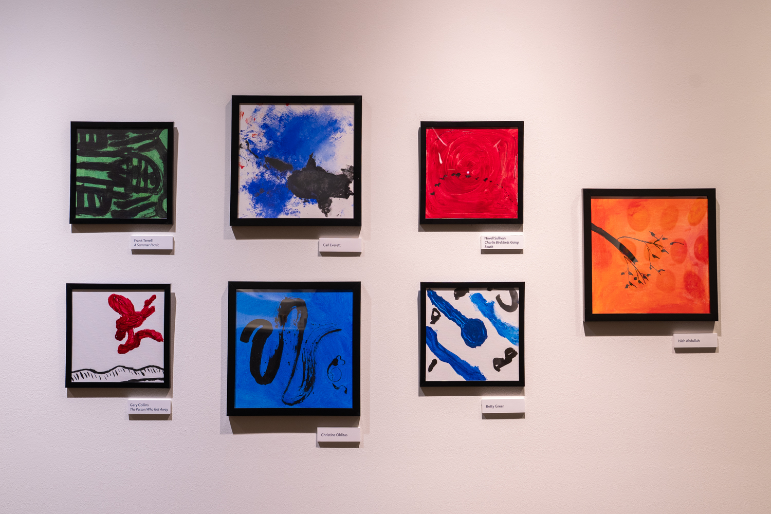 Seven colorful artworks displayed on a wall