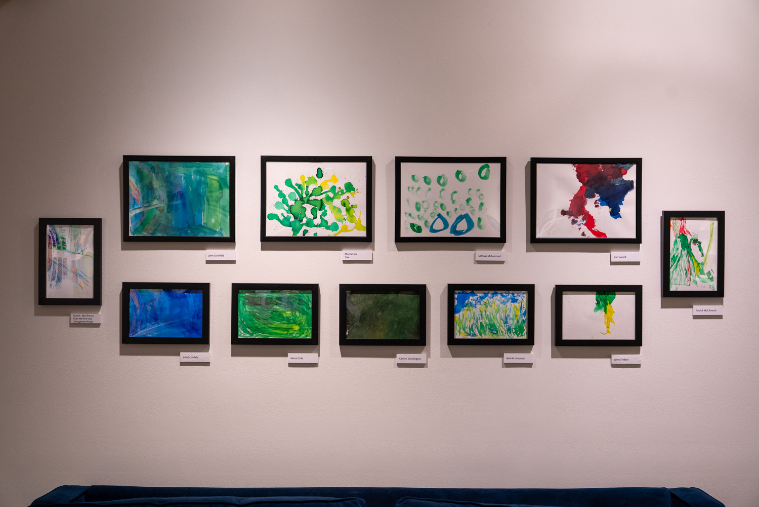 Eleven framed artworks displayed on a wall