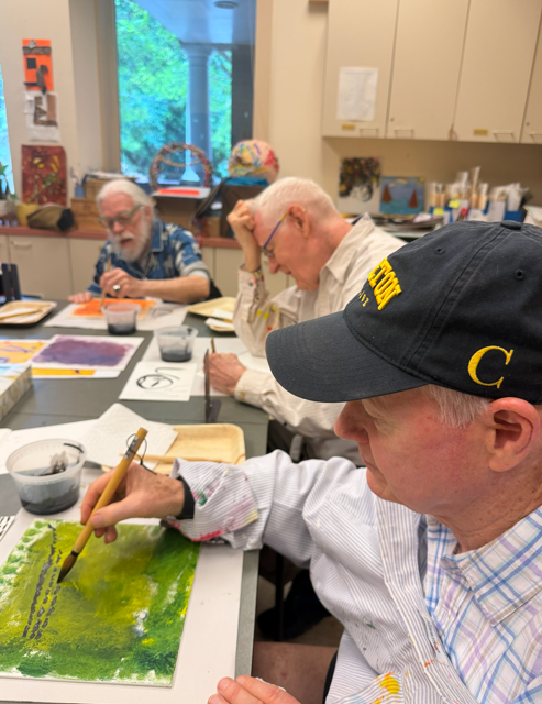 Photograph of three older adults creating art around a table
