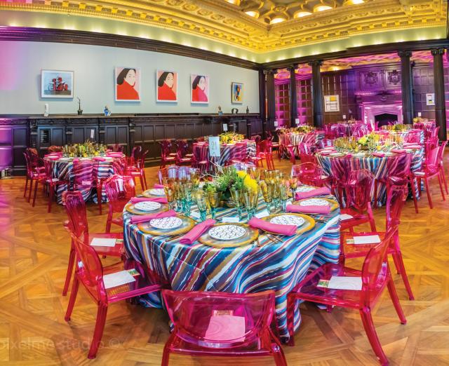 Photograph of room with very elaborate set up of table and chairs for a fancy event.