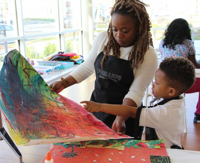 A mother and son creating a painting together in a room with a lot of windows