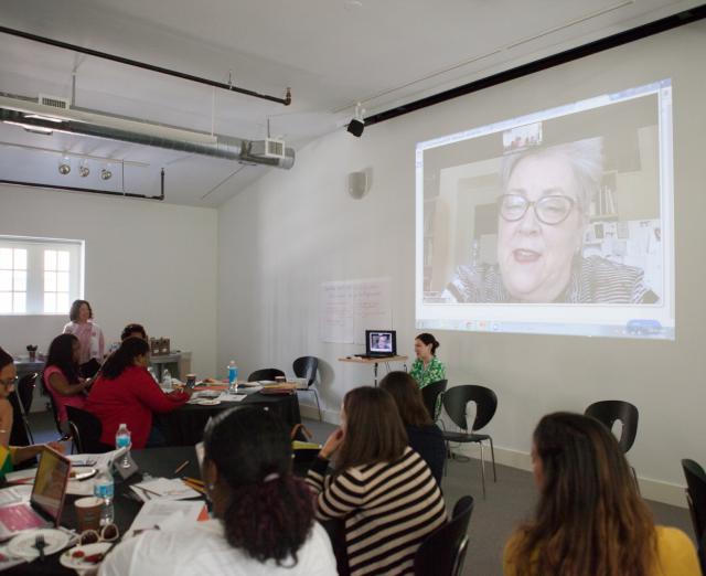 Photograph of the Center Studio with people at tables watching an image projected on the wall