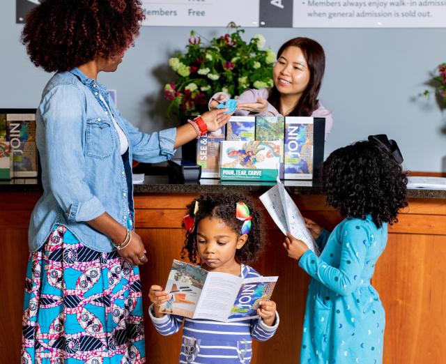 Photograph of three visitors at the admissions desk