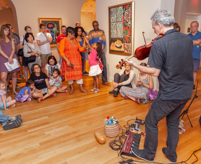 A crowd of people in a gallery watching someone play the violin