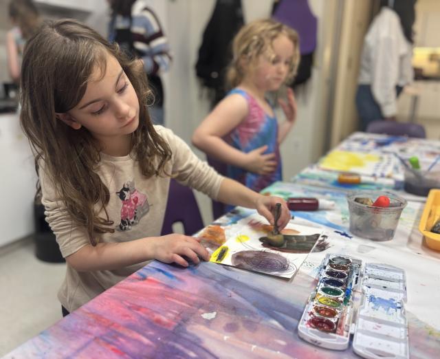 Two children sitting at a table painting