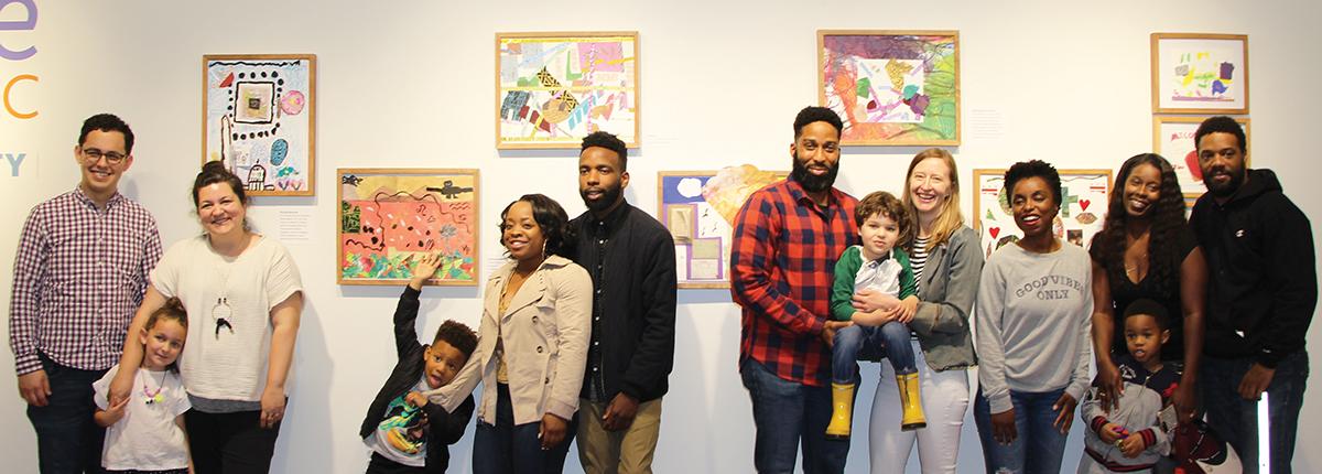 Families standing in front of their artwork created through the Phillips and AppleTree Early Learning Institute partnership