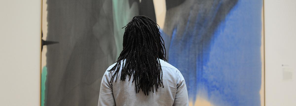 Photograph of the back of a man looking at a very large painting