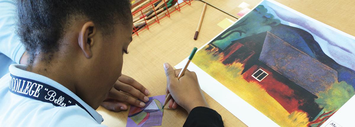 Photograph of student drawing with a print out of an artwork next to her
