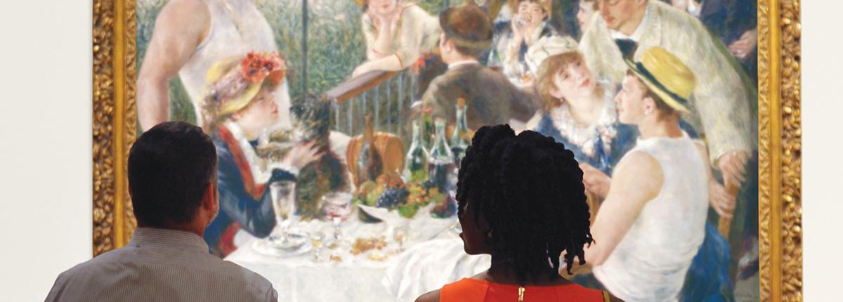 Two people sitting on a bench looking at Renoir's Luncheon of the Boating Party