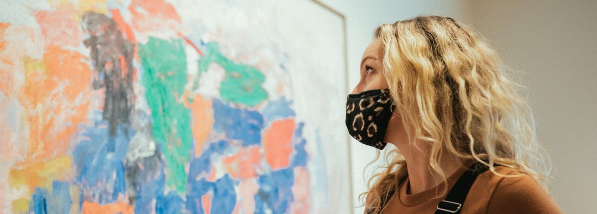 Visitor with mask on looking at painting by Philip Guston