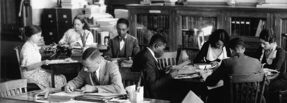 Black and white photograph of people researching at the Schomburg Center, a branch of the New York City Public Libraries.