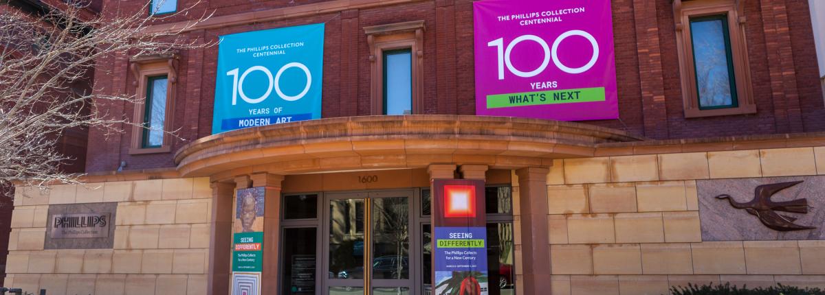 Photo of the main entrance of The Phillips Collection with blue and pink banners with "100" on them