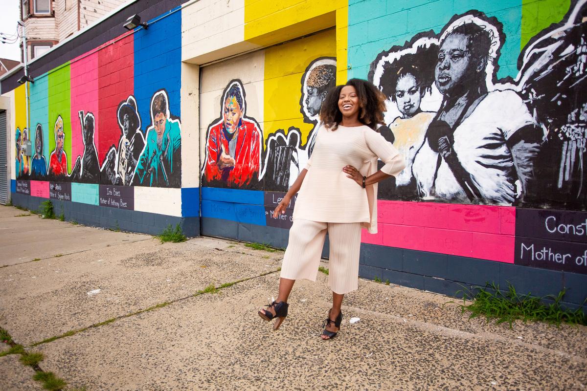 Photograph of Sophia Dawson standing in front of colorful murals