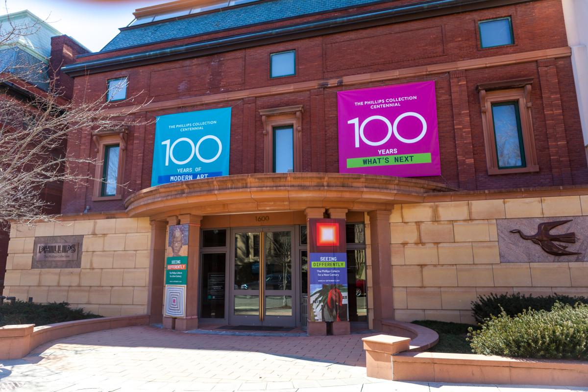 Photo of the main entrance of The Phillips Collection with blue and pink banners with "100" on them