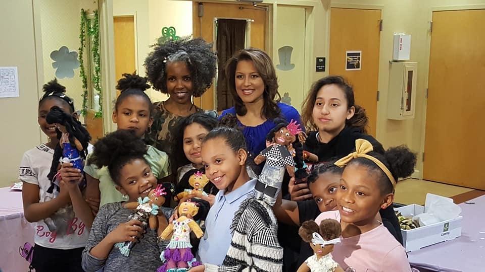 Photo of group of African American girls smiling and holding black dolls