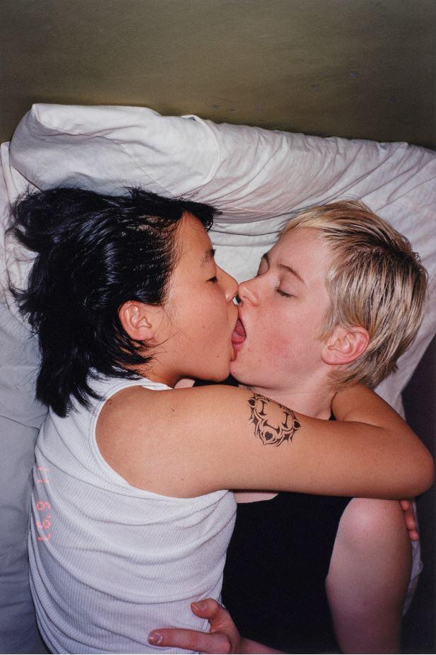 Photograph of two women kissing in bed