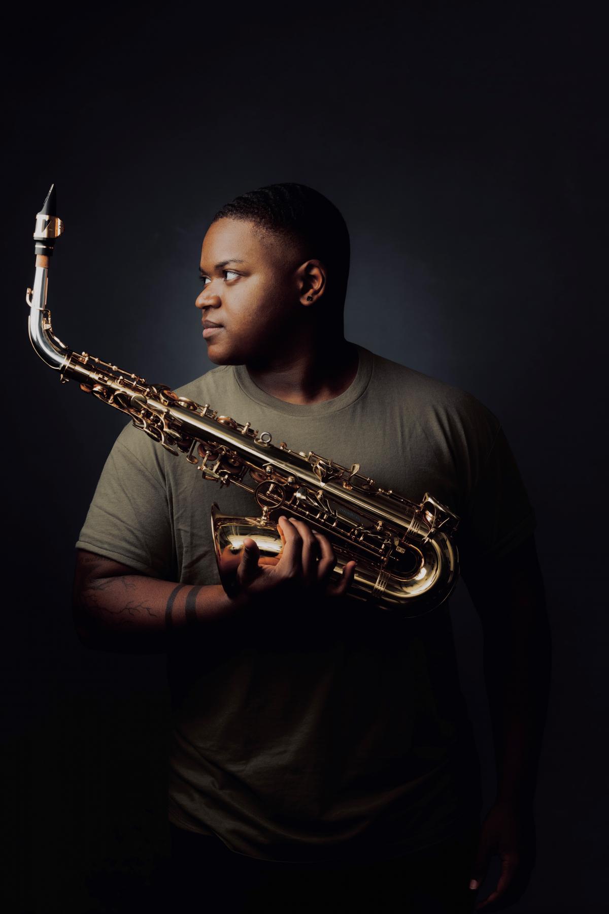 Headshot of Langston Hughes II holding a saxophone