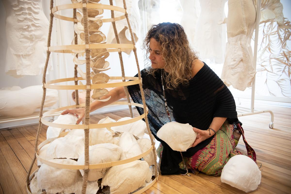 A woman sitting on the floor arranging round objects in a sculpture
