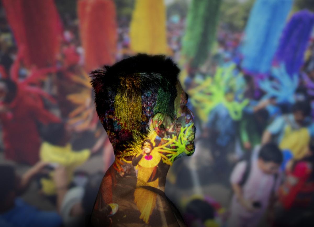 Portrait of a person turned award from camera, with an image of a colorful celebration projected on him