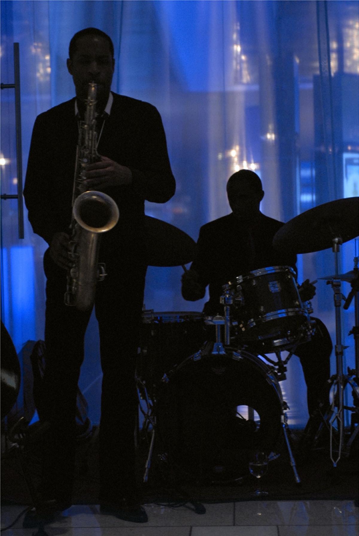 Photograph of two people playing musicians with blue background