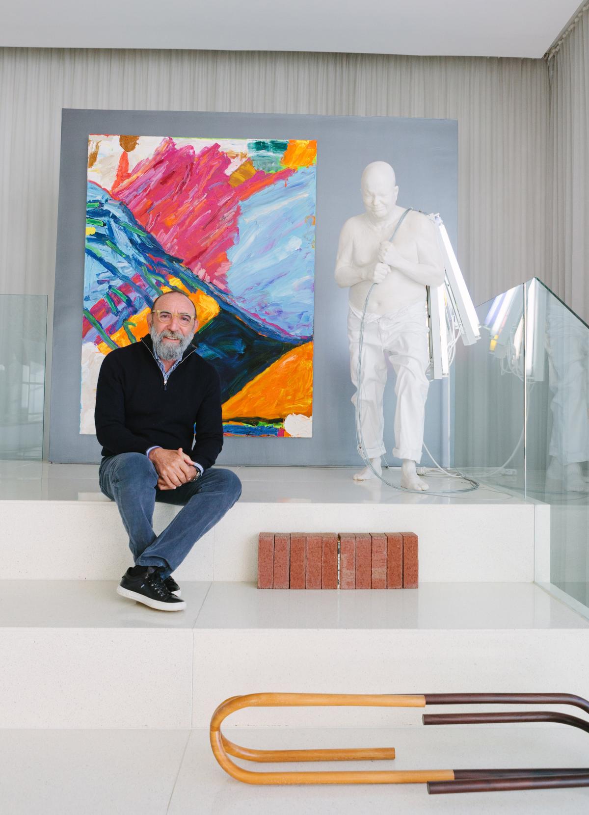 Dani Levinas sitting in his home surrounded by art