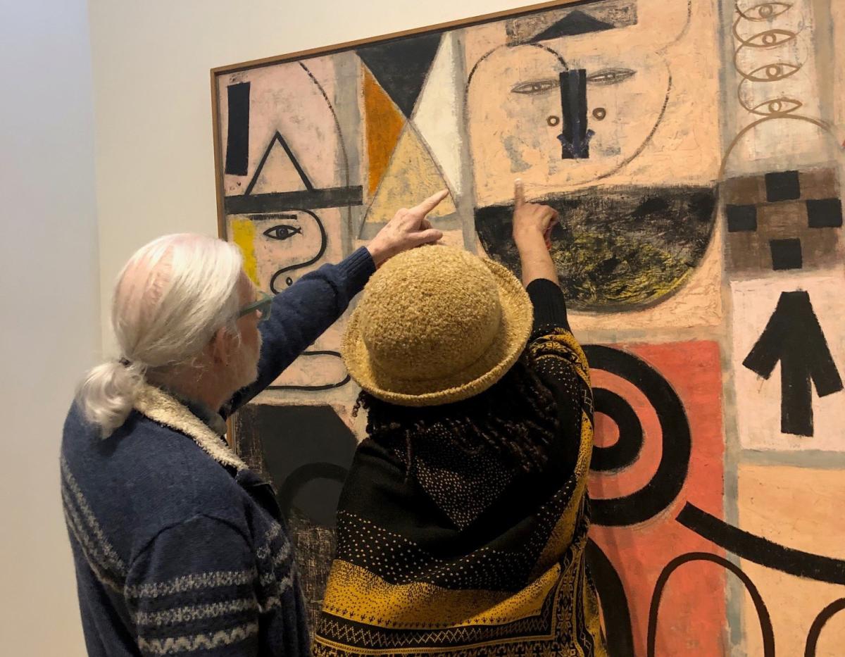 Photograph of two people pointing at an artwork