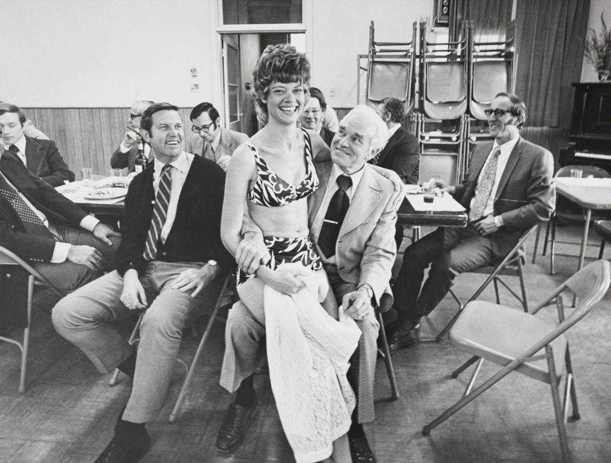 Bill Owens, Untitled (Group of men and one young lady on sitting on lap of older gentleman.), c. 1972.