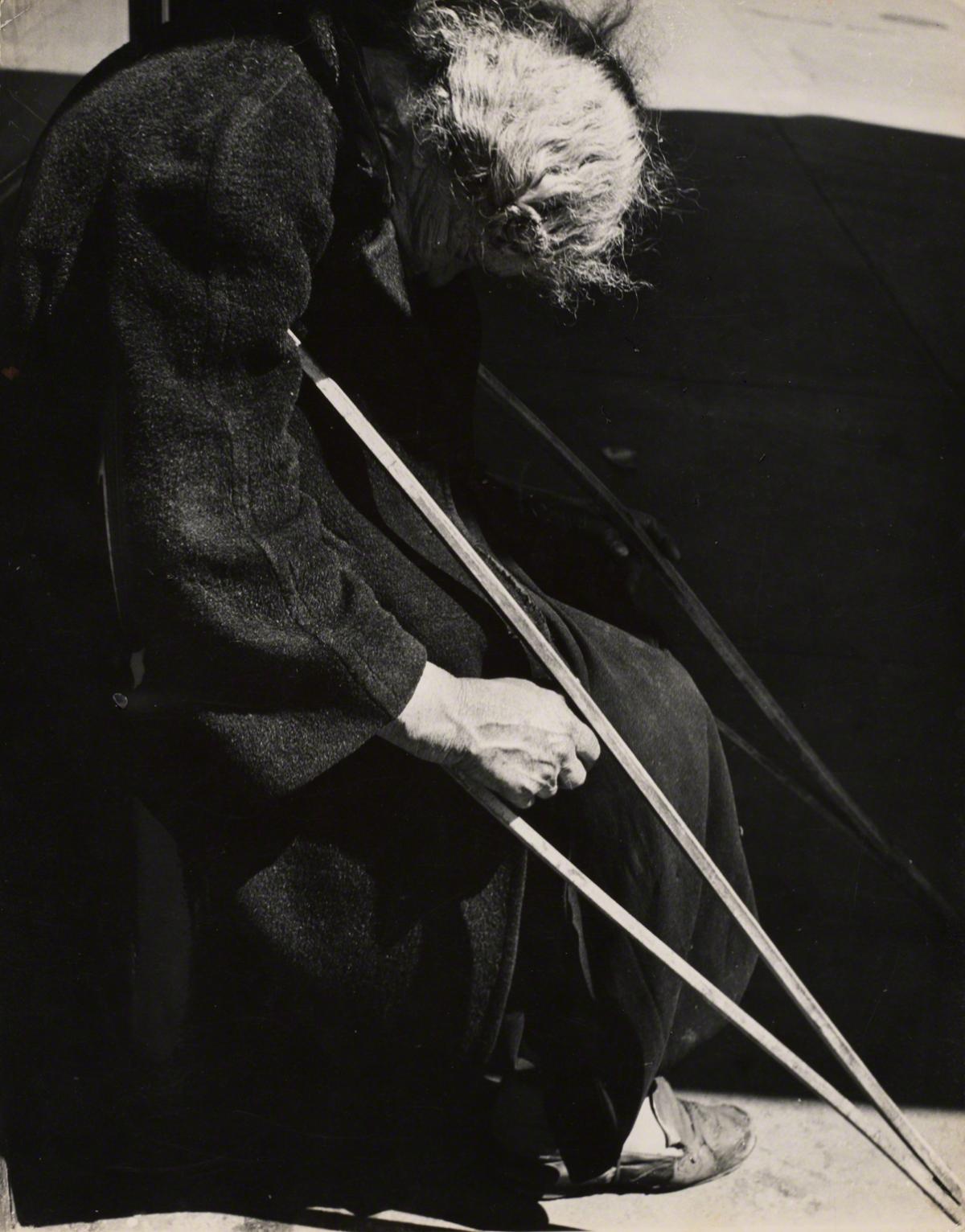 Leon Levinstein, Untitled (woman with crutches), not dated.