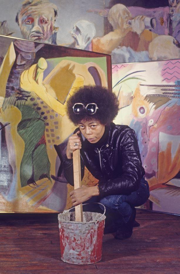 Vivian Browne kneeling in front of her paintings